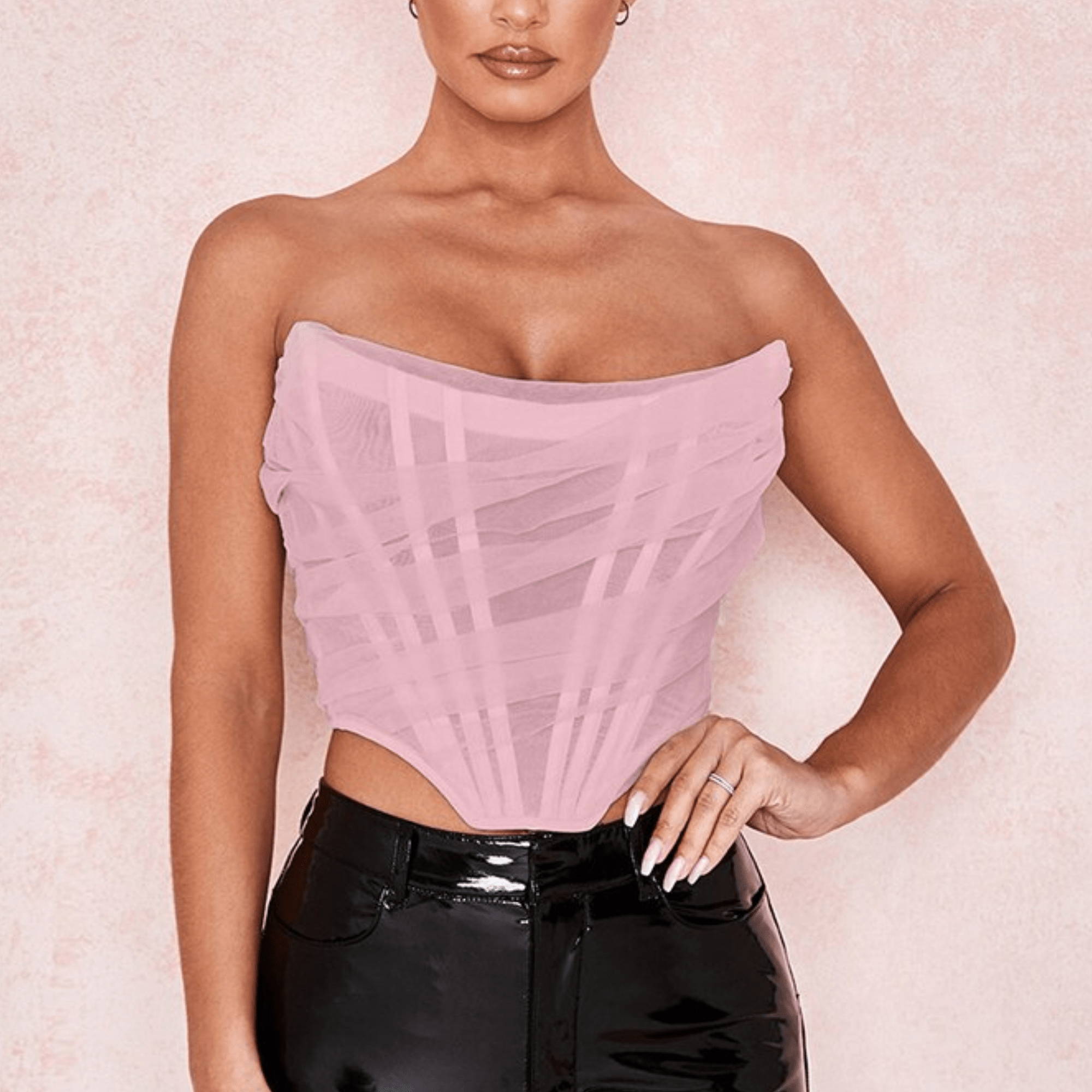 Modelo feminina vestindo corset estruturado com camadas de tule translúcido e acabamento drapeado em diagonal. Modelagem tomara que caia com recorte em V na barra. Estética moderna e elegante, ideal para composições ousadas e sofisticadas.
