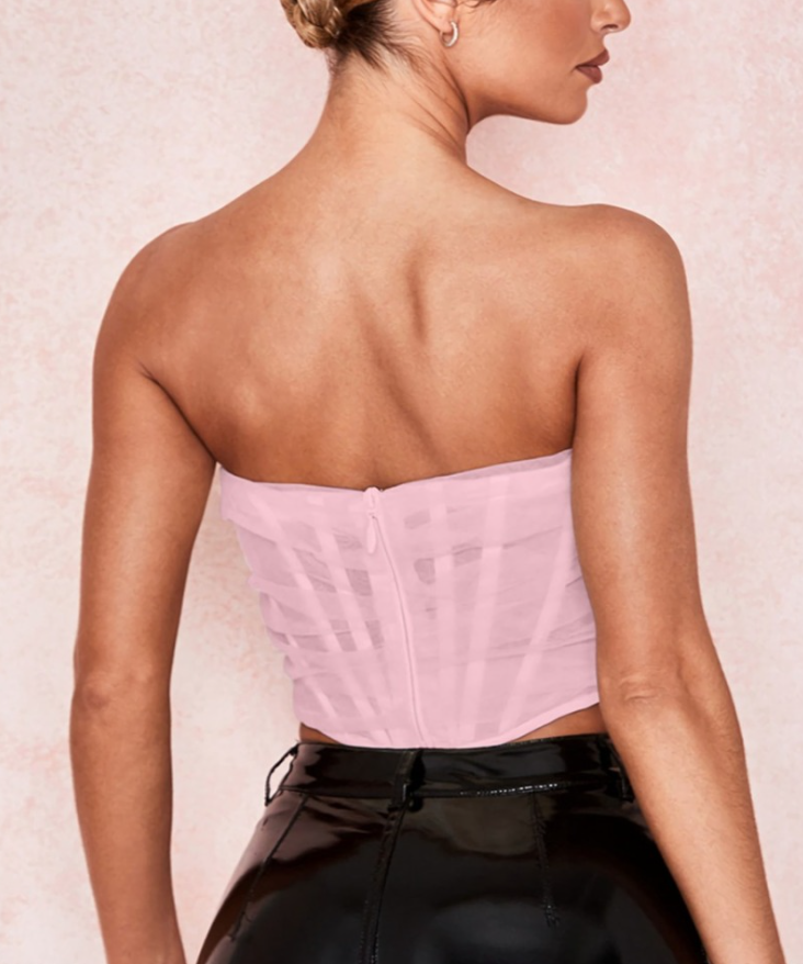 Modelo feminina vestindo corset estruturado com camadas de tule translúcido e acabamento drapeado em diagonal. Modelagem tomara que caia com recorte em V na barra. Estética moderna e elegante, ideal para composições ousadas e sofisticadas.