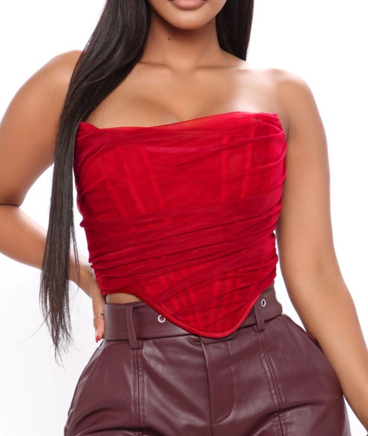 Modelo feminina vestindo corset estruturado com camadas de tule translúcido e acabamento drapeado em diagonal. Modelagem tomara que caia com recorte em V na barra. Estética moderna e elegante, ideal para composições ousadas e sofisticadas.
