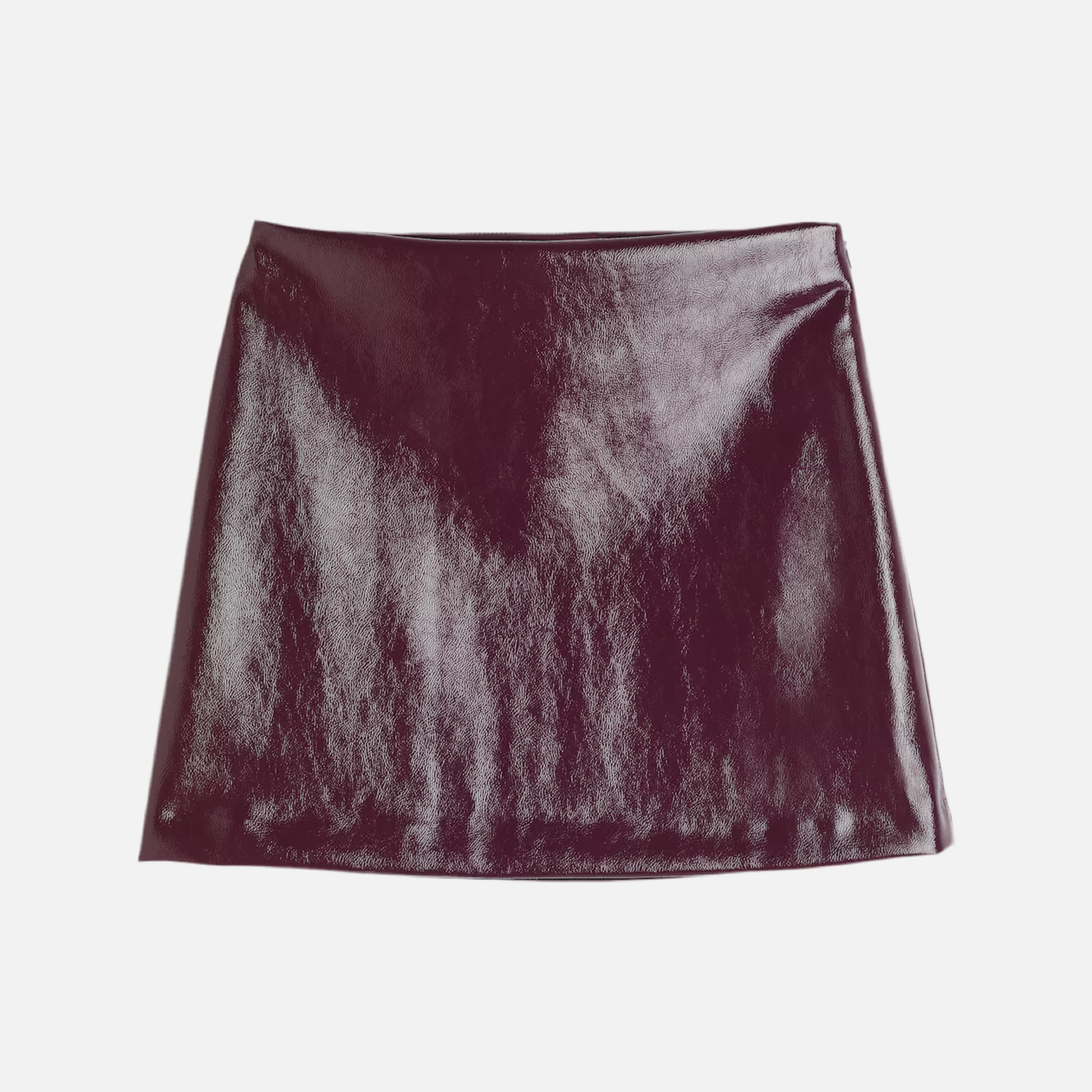 saia de couro com modelagem reta e justa, comprimento mini, acabamento brilhoso e detalhe de cinto discreto na cintura. A peça valoriza o quadril e tem estética urbana, sexy e sofisticada.
