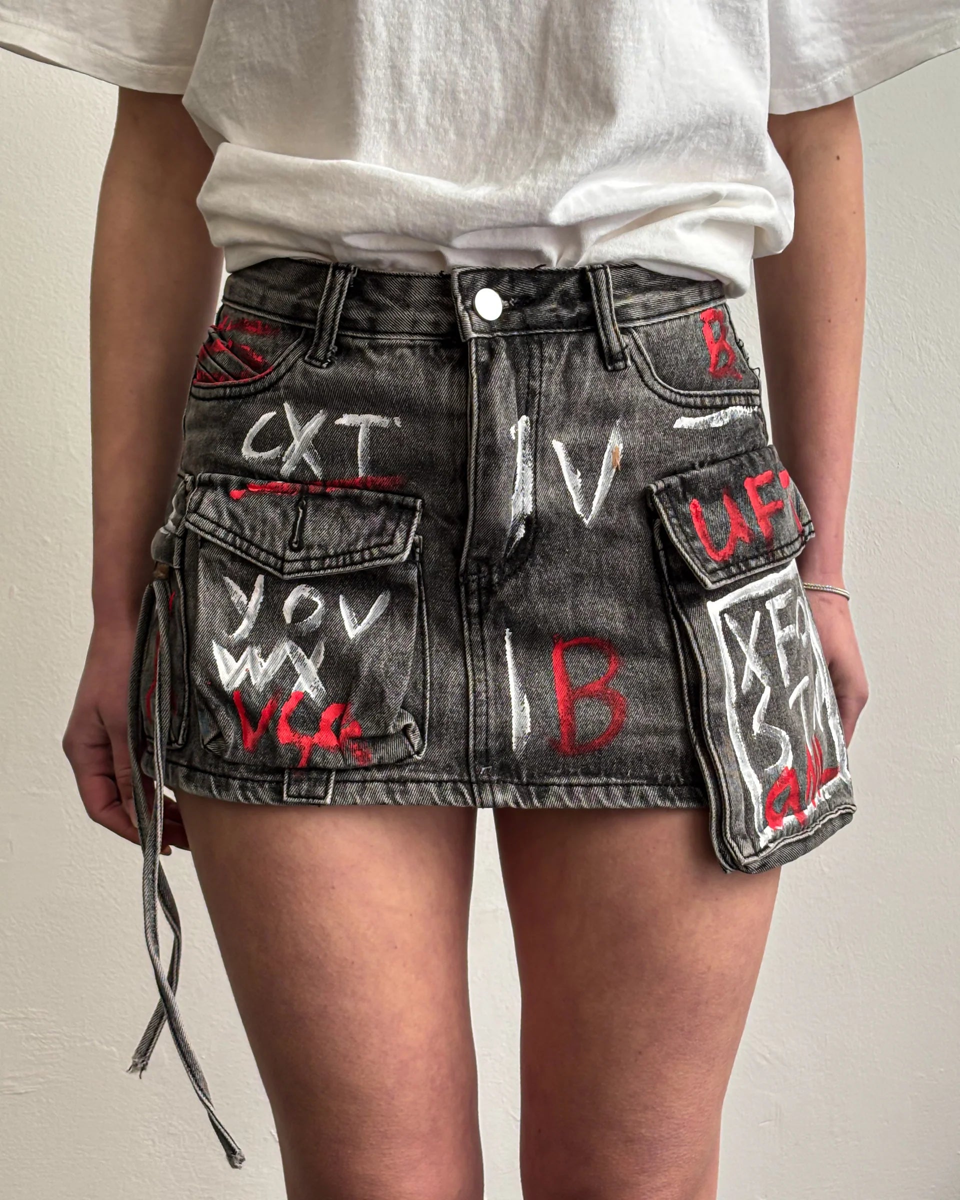 Saia jeans com estampa grafitada em tons vibrantes e bolsos cargo utilitários com lapela. Modelagem mini com cintura média e estrutura reta. Visual urbano, ousado e expressivo, com toque de arte de rua e atitude fashion.