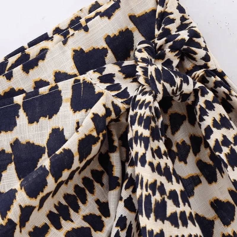 Saia feminina transpassada com estampa tribal, amarração frontal ajustável e aplicação de pompons na barra. Caimento leve, tecido fluido e cintura baixa, ideal para composições tropicais, boho chic ou looks de verão com atitude.