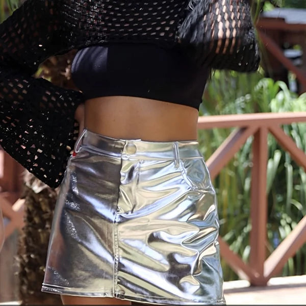 Saia mini metalizada em material sintético com acabamento espelhado. Modelagem ajustada com cós tradicional, bolsos e recorte central. Ideal para looks noturnos ousados, baladas e produções com brilho e atitude.